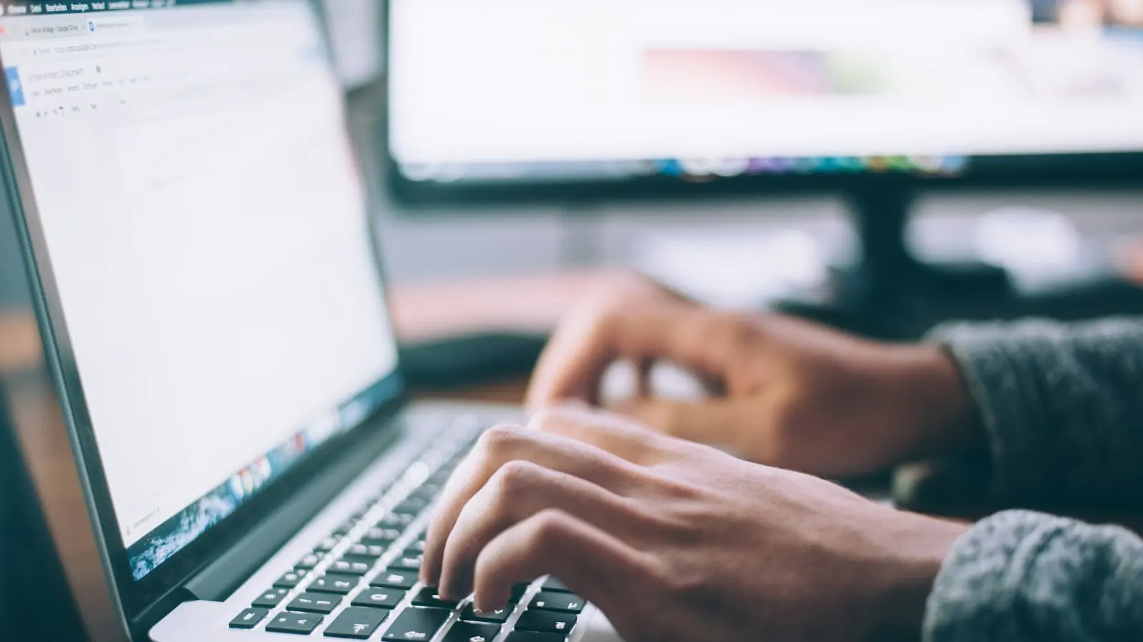 IT technician working on a laptop remotely while viewing a support ticket queue